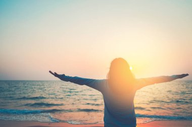 Sahilde ve adada, günbatımında gökyüzünde yükselen kadın mekânını kopyalayın. Özgürlük ve seyahat macera konsepti. Klasik ton filtre efekti renk biçimi.