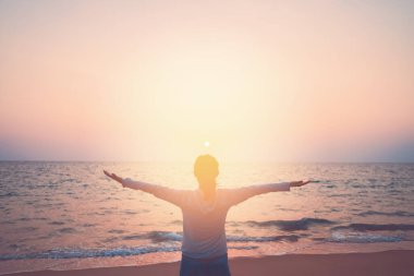 Sahilde ve adada, günbatımında gökyüzünde yükselen kadın mekânını kopyalayın. Özgürlük ve seyahat macera konsepti. Klasik ton filtre efekti renk biçimi.