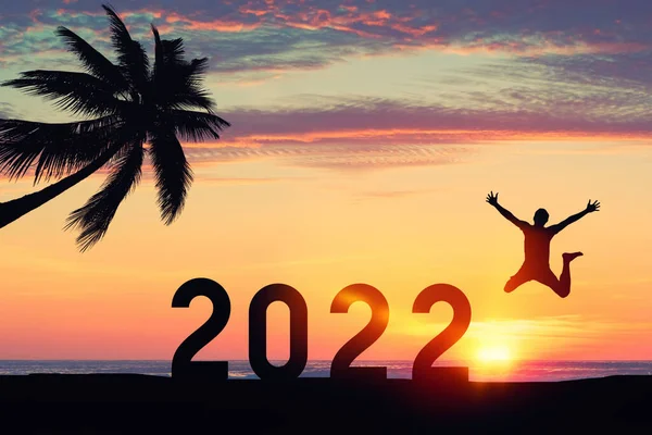 2022年のような数でジャンプするシルエットの男と日没の空の抽象的な背景に熱帯のビーチでヤシの木 お正月や休日のお祝いのコンセプト ヴィンテージトーンフィルターカラースタイル — ストック写真