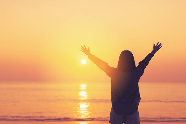 Copy space of woman rise hand up on sunset sky at beach and island background. Freedom and travel adventure concept. Vintage tone filter effect color style.