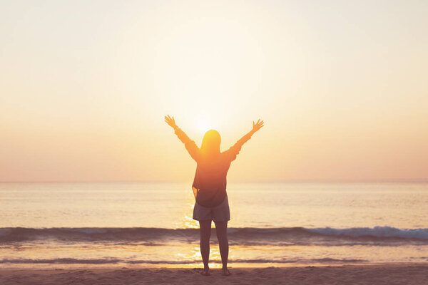 Copy space of woman rise hand up on sunset sky at beach and island background. Freedom and travel adventure concept. Vintage tone filter effect color style.
