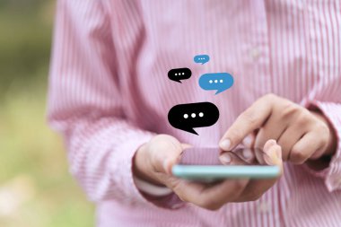 Açık doğa parkı arka planında sohbet ikonu olan akıllı bir telefon kullanarak kadın el ele tutuşunu kapat. Teknoloji ve seyahat tatil konseptinin kopyalama alanı. Klasik ton filtre efekti rengi.