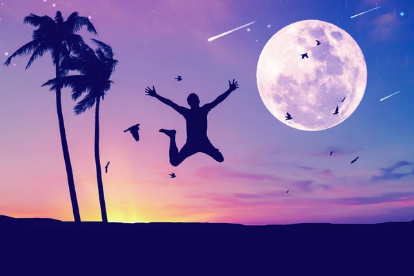 Man jumping and birds flying with palm tree at tropical sunset beach full moon abstract background. Freedom feel good and travel adventure concept. Vintage tone filter effect color style.