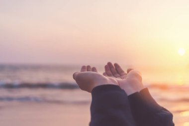 Kadın, tropik günbatımı arka planında elini kaldırıyor. Klasik ton rengi.