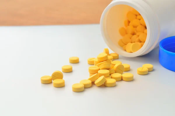 Gelbe Medikamententablette und offene Flasche mit Medikamenten — Stockfoto