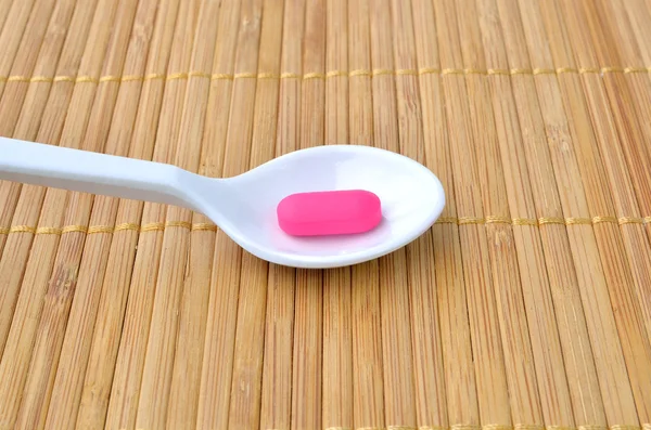 Comprimido de medicamento rosa na colher — Fotografia de Stock