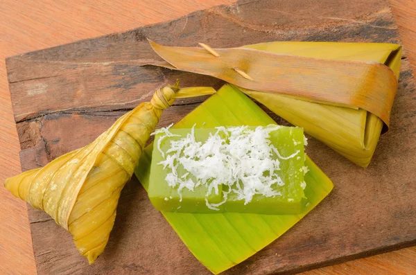 Thai dessert sticky rice wrapped in banana leaf on wood background. — Stock Photo, Image