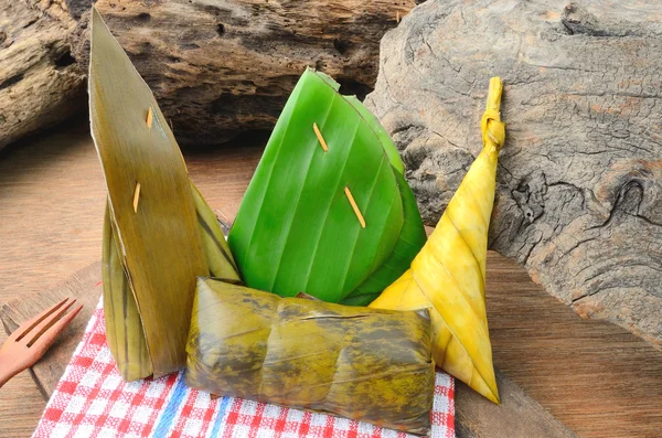 Thai dessert sticky rice wrapped in banana leaf on wood background. — Stock Photo, Image