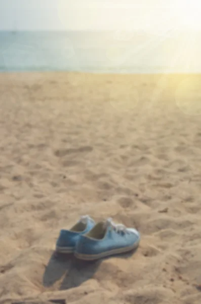 Zapatos borrosos en la playa con destello de sol — Foto de Stock