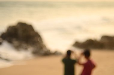 Adam ve kadın alarak fotoğraf ile akıllı telefon plaj arka plan bulanıklık.