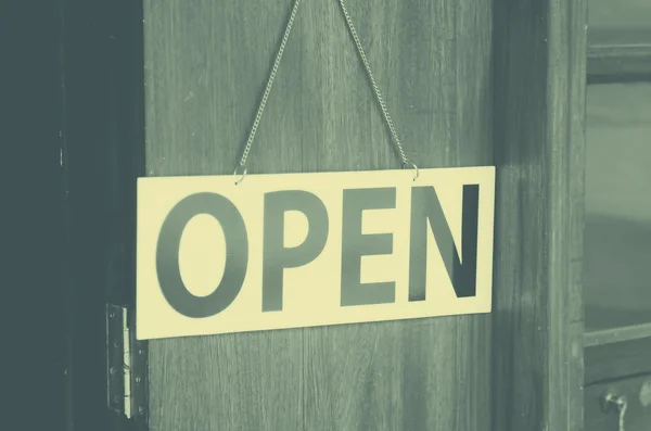 Open sign broad hanging on wooden door in street cafe.