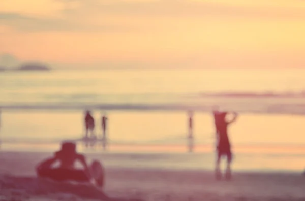 Flou les gens se détendre sur la plage coucher de soleil tropical fond abstrait. . — Photo