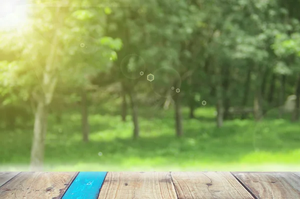 Verwischen Natur grünen Park mit Sonnenlicht auf alten leeren Holztisch Hintergrund. — Stockfoto