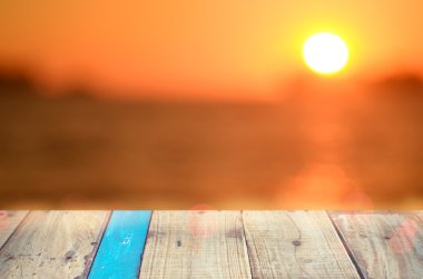 Tropikal günbatımı plaj ile eski boş ahşap masa arka plan bulanıklık.