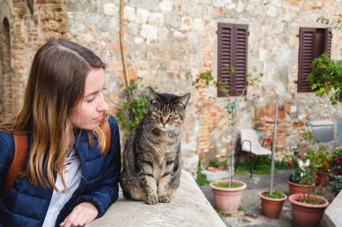 Genç kız bir kedi ile hoş bir sohbet San Gimignano içinde yaşıyor. Toskana, İtalya