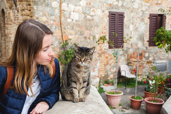 Genç kız bir kedi ile hoş bir sohbet San Gimignano içinde yaşıyor. Toskana, İtalya