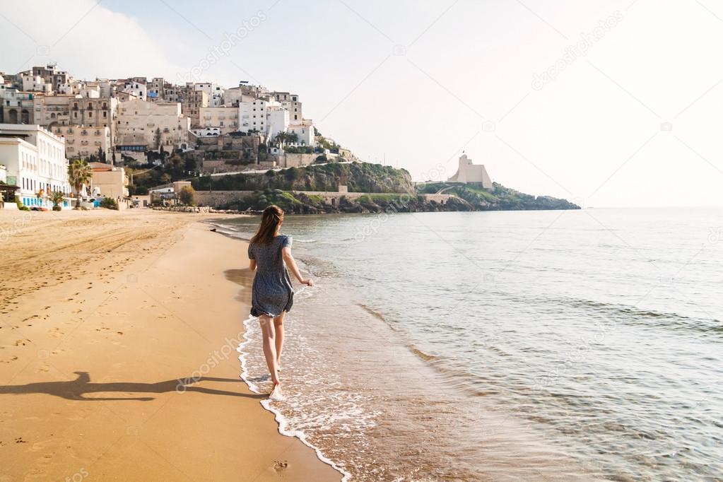 Young girl running on the beach of Sperlonga, Italy