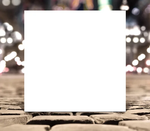 Bannière de gabarit de papier carré blanc vierge sur les briques de chaussée de route avec fond flou — Photo