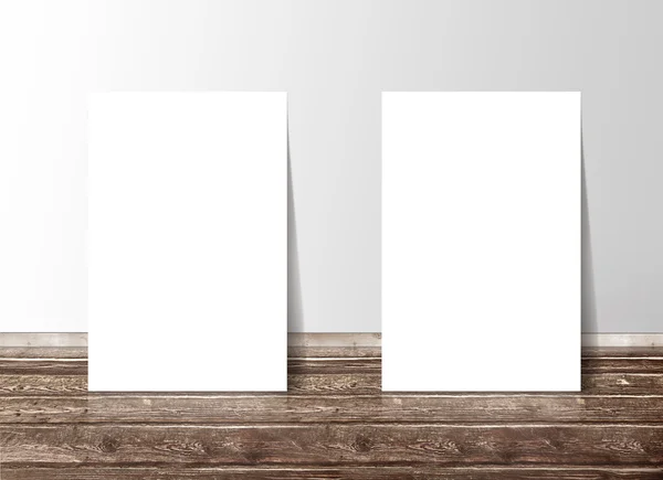 Duvara karşı ahşap yerde iki boş beyaz kağıt şablonu afiş — Stok fotoğraf