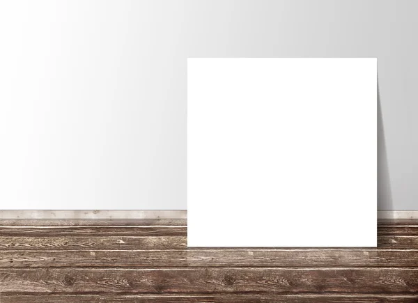 Blank white square paper template banner on the wooden floor against the wall — Stock Photo, Image