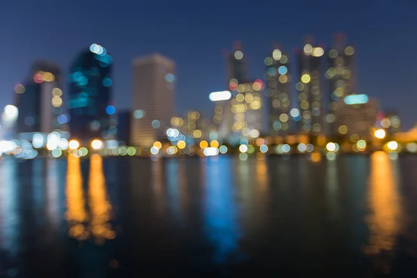 Noite borrão bokeh luzes escritório edifício água reflexão, fundo abstrato — Fotografia de Stock