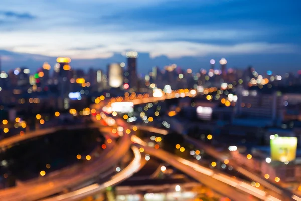 Abstrato luz embaçada no crepúsculo, viaduto estrada trocada com a cidade do centro — Fotografia de Stock