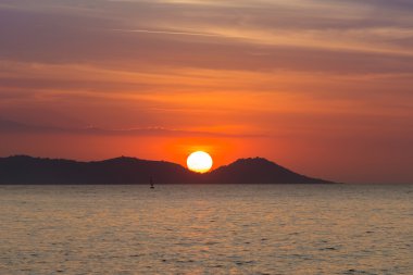 Günbatımı sahil üzerinde dağın arkasında