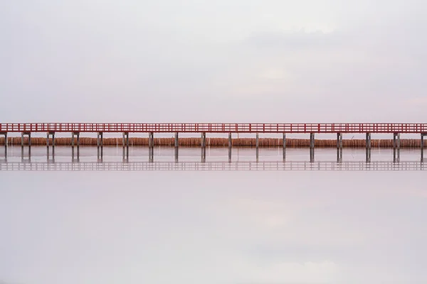 Chodící dřevěný most přes moře s vodou reflexe — Stock fotografie