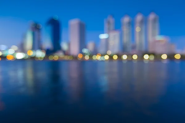 Out of focus big city lights with water reflection during twilight — Stock Photo, Image