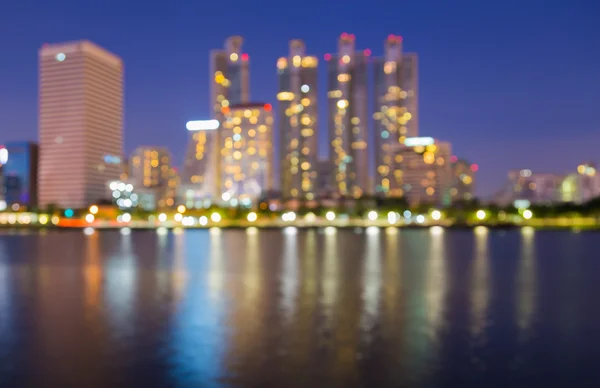 Fora de foco grandes luzes da cidade à noite com reflexão de água — Fotografia de Stock