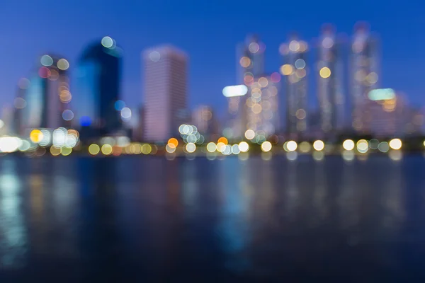 Fora de foco cityscape à noite, Bokeh foto borrada com reflexão de água — Fotografia de Stock