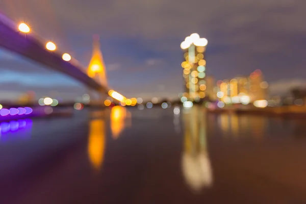 Abstract bokeh light of Suspension Bridge and office building waterfront view — Stock Photo, Image