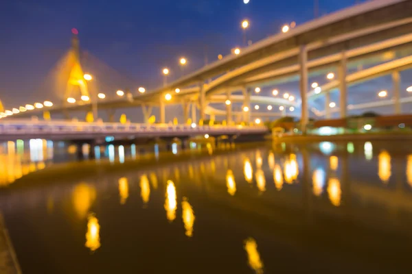 Borroso bokeh ciudad luces carretera con puente colgante — Foto de Stock