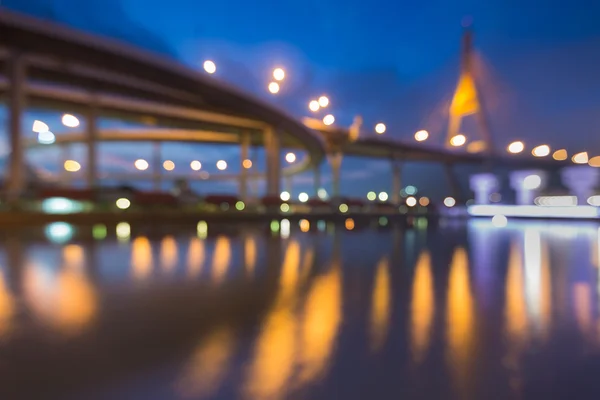 Abstract blurred bokeh light of suspension bridge with water reflection during twilight — Stock Photo, Image