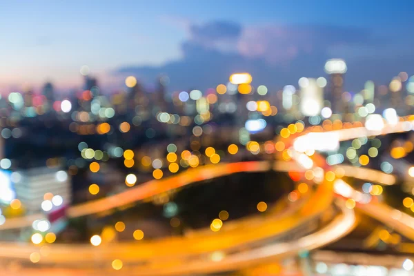 Desfocado bokeh cidade centro da estrada trocada após o pôr do sol — Fotografia de Stock