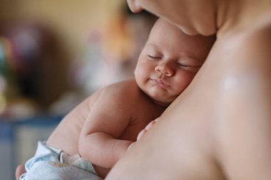 Onu sevgiyle kucaklayan annesinin kollarında yeni doğmuş bir bebek..