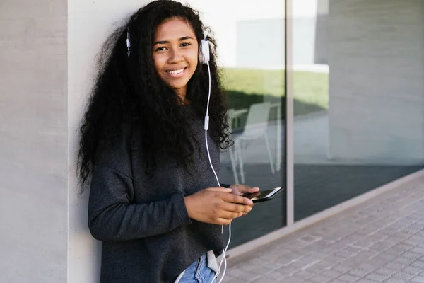 Mulher afro bonita ouvindo música com fones de ouvido brancos — Fotografia de Stock