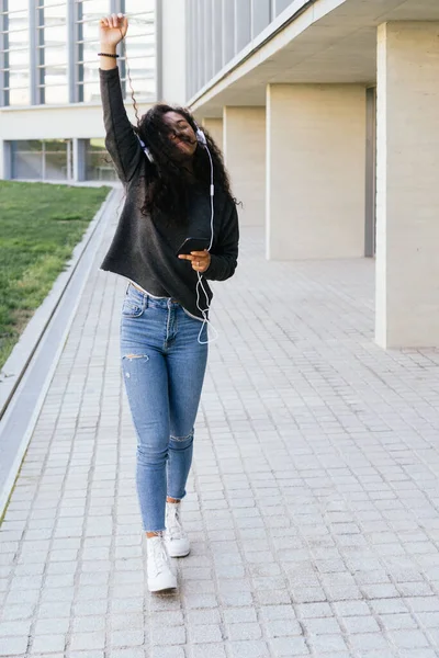 Menina afro bonita dançando com fones de ouvido brancos — Fotografia de Stock