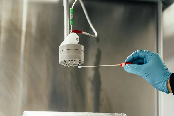 scientist working with an electrospinning machine in the lab creating nanofibers. Electrospinning results in a liquid polymer solution in many nanofibers that provide a surface to deposit the MOFs.