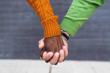 El ele tutuşun. Siyah ve beyaz eller arka planda bir arada. Arkadaşlığın ve aşkın sembolü olarak el ele tutuşan çok ırklı bir çift..