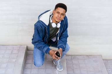 Sokaktaki afro çocuk kulaklıklı cep telefonunu kullanıyor.. 