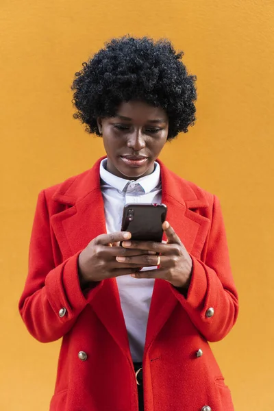 Bela mulher afro-americana segurando um telefone celular, escreve uma mensagem de texto. — Fotografia de Stock