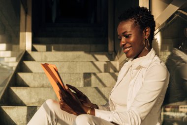 Zenci kızın oyun oynamak ve ders çalışmak için portatif dokunmatik ped kullanışının yan görüntüsü.