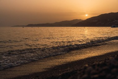Gün batımında sahilin sakin sahnesi.