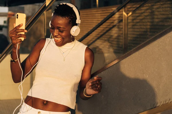 Sokakta müzik dinlemekten zevk alan mutlu Afrikalı Amerikalı kadın dans ediyor..