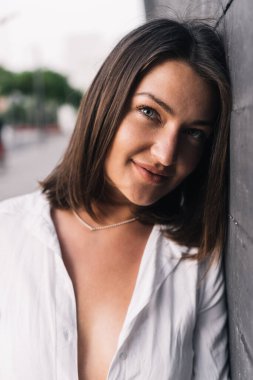 Yakından bakınca şık bir kadının kameraya baktığı ve sokakta siyah bir duvara yaslanırken gülümsediği görülüyor. Şehir konsepti.