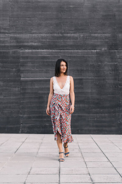 Brunette woman in stylish summer clothes walking outdoors on the street.