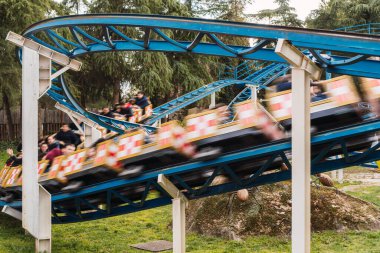 Lunaparktaki lunaparkta hız treninin raylarında hızla giden bir araba görüntüsü.