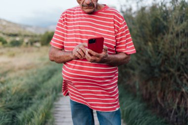 Yetişkin bir adam dışarıda dikilirken akıllı telefonunu kontrol ediyor..