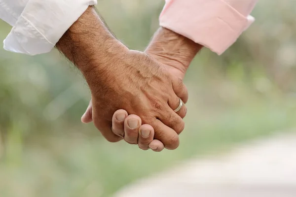 Close up vista de um casal gay ternamente de mãos dadas enquanto desfruta de um passeio juntos ao ar livre. — Fotografia de Stock